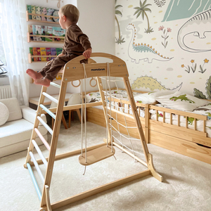 Parque infantil coberto de madeira com balanço, argolas de ginástica e rede de escalada